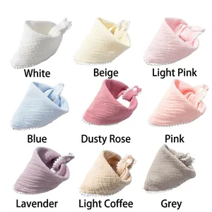 Detail view of nine cotton baby bibs in various colors with decorative lace edging