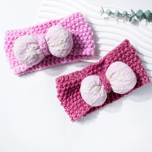 Close-up of knit baby headbands with embroidered floral bow tie in pink and magenta