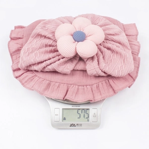 Cappellino rosa in maglia neonato con volant e fiore 3D del peso di 51,5g sulla bilancia