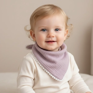 Detail of light purple cotton gauze baby bib with white pom-pom trim on a model