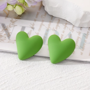 Detailed close-up of matte lime green heart studs on a minimalist marble background