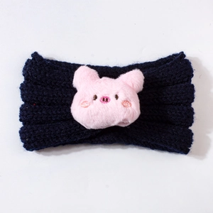 Detail of navy blue knitted baby headband with a cute pink plush pig embroidery