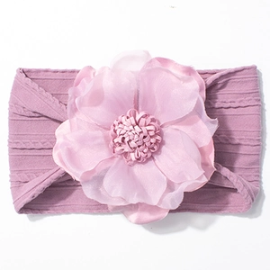 Détail d'un bandeau bébé avec grande fleur en mousseline rose et texture tricotée violette