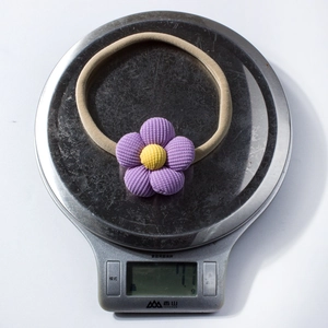 Dettaglio di una fascia a fiore in velluto viola su bilancia digitale da 7,1g