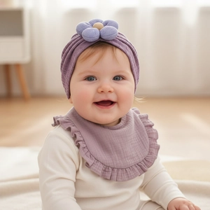 Dettaglio del turbante neonato viola con fiore e bavaglino coordinato con bordi a balze