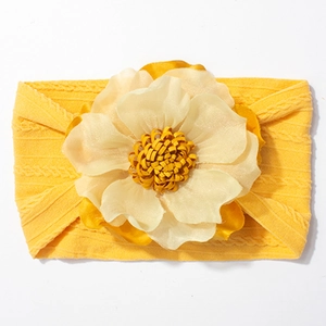 Détail d'un bandeau bébé en maille torsadée jaune avec une grande fleur en tissu multicouche