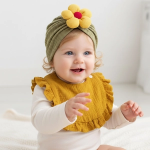 Dettaglio cappello baby turban verde oliva con fiore giallo e bavaglino con volant