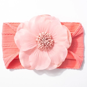 Gros plan sur un bandeau bébé côtelé rose avec une fleur en tissu multicouche délicate