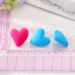 Close-up of matte magenta and blue heart earrings showing 2cm size on a ruler