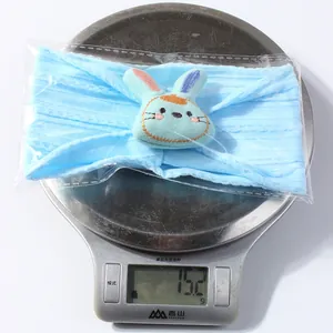 Close-up of a blue baby headband with a cute bunny design on an electronic scale showing 15.2g