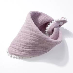 Detail view of light purple muslin cotton baby bib with white pom-pom trim and snap button