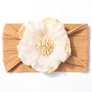 Détail d'un bandeau pour bébé en tricot jaune moutarde avec une fleur en soie crème
