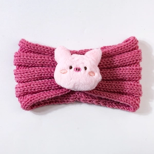 Detail of pink knitted baby headband featuring a plush pig decoration for winter warmth