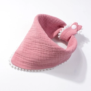 Detailed view of pink muslin cotton baby bib with white pom-pom trim and snap closure
