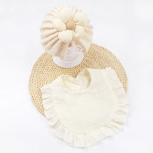 Dettaglio del turbante beige per neonati con fiore 3D e bavaglino a balze coordinato