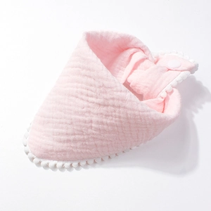 Detailed view of pink cotton baby bib with pom-pom trim and snap button closure