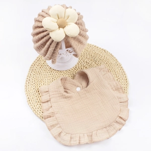 Dettaglio del cappello floreale per neonati e set di bavaglini con volant in cotone kaki