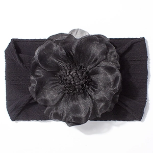 Détail d'un bandeau pour bébé avec une grande fleur noire en mousseline et tissu tricoté