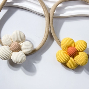 Dettaglio di fasce per capelli con fiori di velluto a coste beige e giallo su nylon