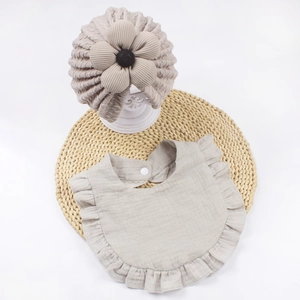 Dettaglio del set cappello jacquard e bavaglino neonato con fiore e bordi a balze