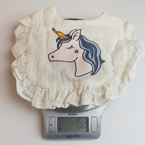 Detail view of 15.3g lightweight pure cotton baby bib with ruffle edge and unicorn print