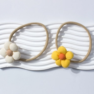 Dettaglio di due fasce elastiche per neonati con fiori in velluto a coste crema e giallo zenzero