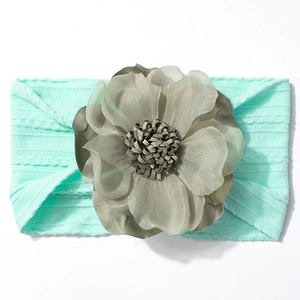 Détail d'un bandeau bébé vert menthe avec grande fleur grise en mousseline et texture tricot