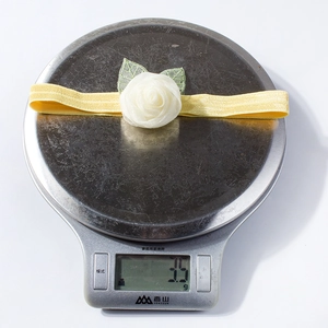 Detail view of yellow baby headband showing weight of 3.5g on a digital scale