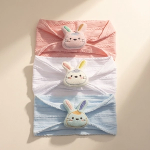 Detailed knit texture of pink, white, and blue baby headbands with plush bunny embroidery