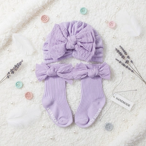 Detail of light purple knitted baby hat and socks set with large decorative bows