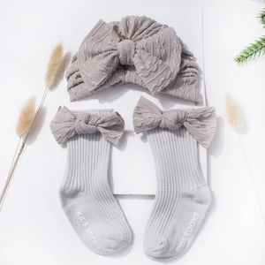 Detail view of cable knit baby hat and socks set with a large bow in soft purple-grey