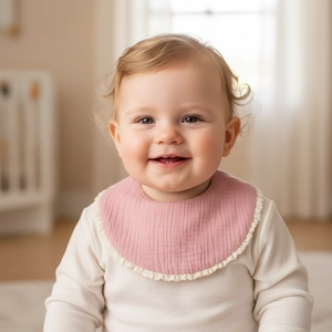 Detail of light pink baby bib with soft gauze texture and delicate white lace trim edge