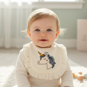 Detail of baby bib with delicate ruffle edges and a cute unicorn embroidery pattern