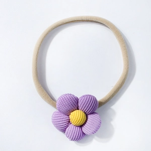 Dettaglio del fiore di velluto a coste viola su fascia elastica gialla per neonati