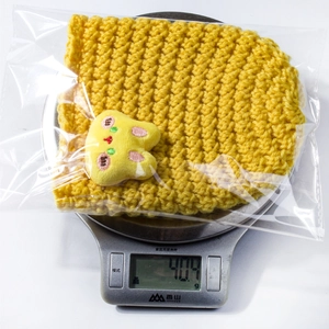 Close-up of yellow knit baby hat with cute cat embroidery on a digital kitchen scale