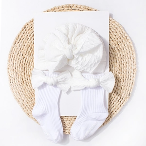 Detail of white knitted baby hat and socks set with large decorative bows for infants