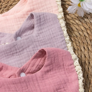 Detailed macro view of soft cotton gauze baby bibs with delicate white lace edges