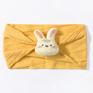 Detail of yellow knit baby headband with cute plush rabbit ornament and cable texture