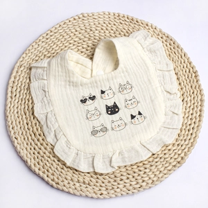 Close-up of baby bib with ruffled edges and cute cartoon cat patterns on cotton fabric