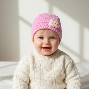 Detailed knit texture of pink baby winter hat featuring a cute 3D cartoon patch