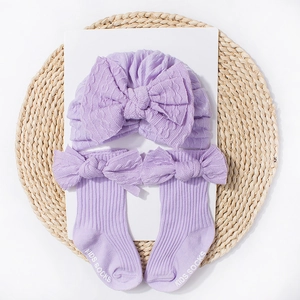 Lavender knitted baby hat and socks set with bow ties on a natural straw mat