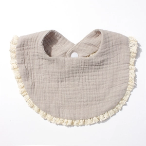 Close-up of cotton baby bib with decorative lace edges and a secure snap button closure