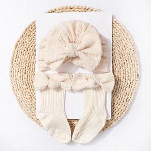 Detailed view of knitted baby hat and socks set with bows on a rustic tray