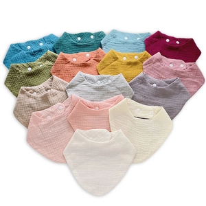Close-up of muslin cotton baby bibs with double snaps and soft crinkle texture details