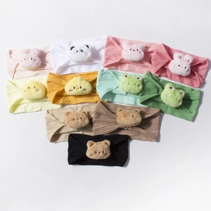 Detailed close-up of 11 colorful ribbed knit baby headbands with cute animal plushies
