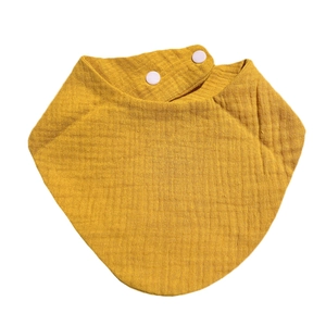 Macro detail of ginger cotton muslin baby bib showing soft crinkle texture and snap buttons