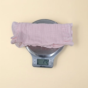 Detailed view of lightweight pink cotton baby burp cloth weighing 27.2g on digital scale