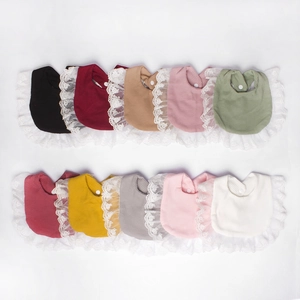 Flat lay of 10 multi-colored cotton baby bibs with delicate white lace trim