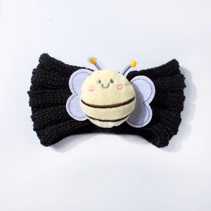 Detail of a black knitted baby headband with a cute plush bee ornament and clear texture