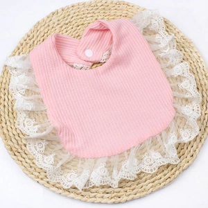Pink waffle cotton baby bib with white lace trim and button, soft and breathable fabric